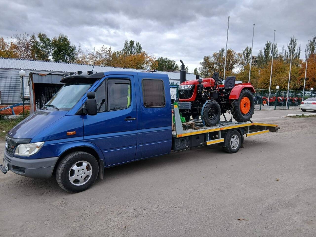 Синій евакуатор перевозить трактор